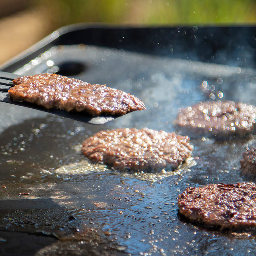 Grilled burger patties cooking on a flat-top griddle.
