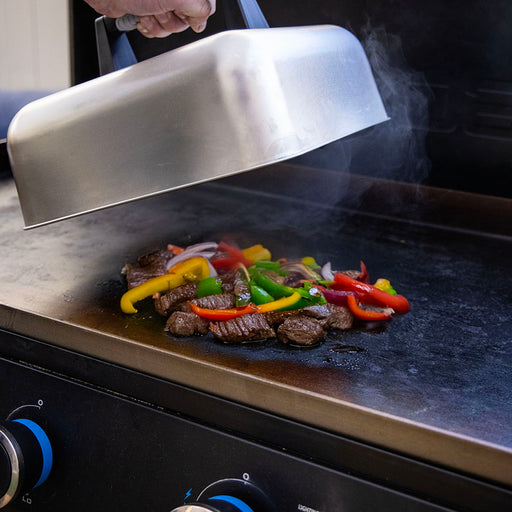 "Grill with silver lid, cooking steak and peppers."