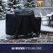 Black all-weather fitted grill cover on outdoor grill in snowy setting.