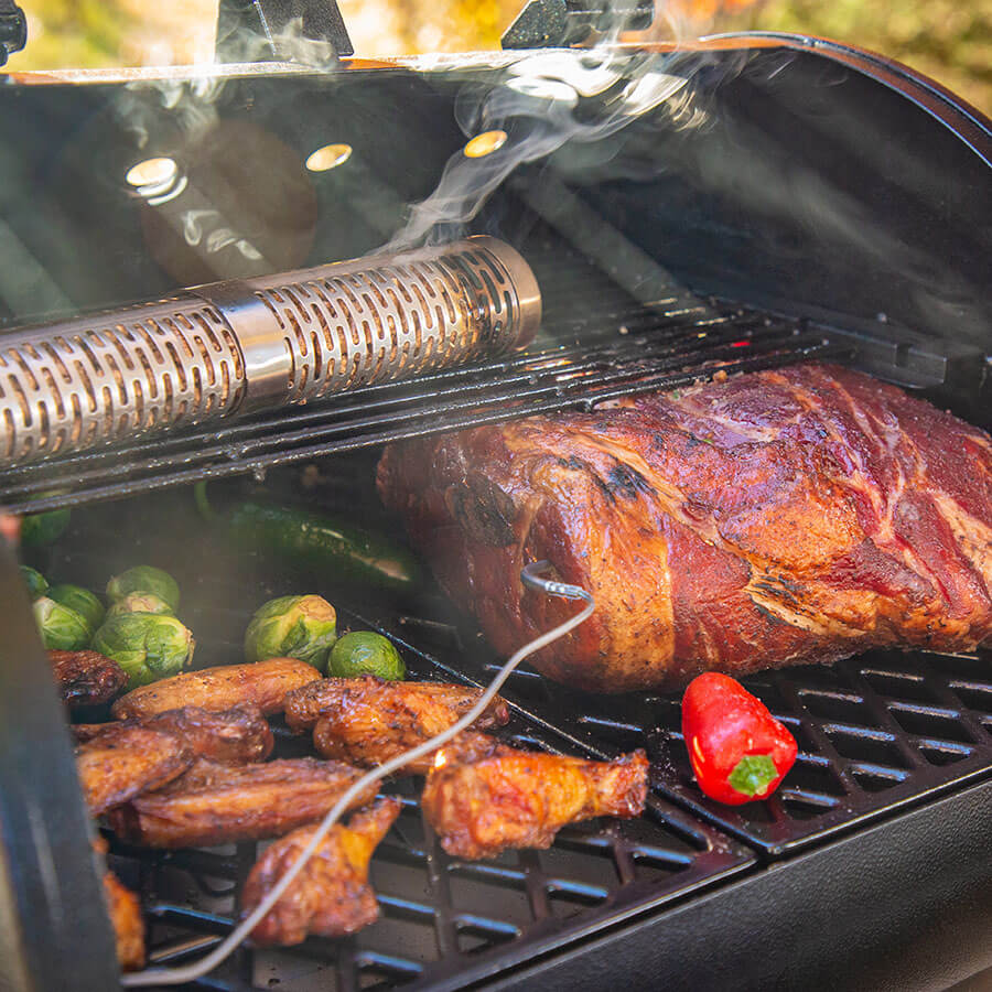Black electric grill with smoking tube, cooking meat, chicken, and vegetables.