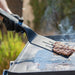 Black spatula flipping burger on grill.