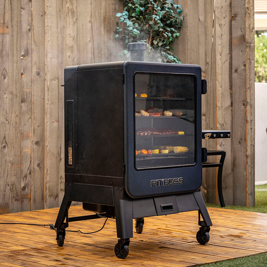 Pit Boss Navigator 6-Series Vertical Smoker, lifestyle with food smoking on grill on backyard patio