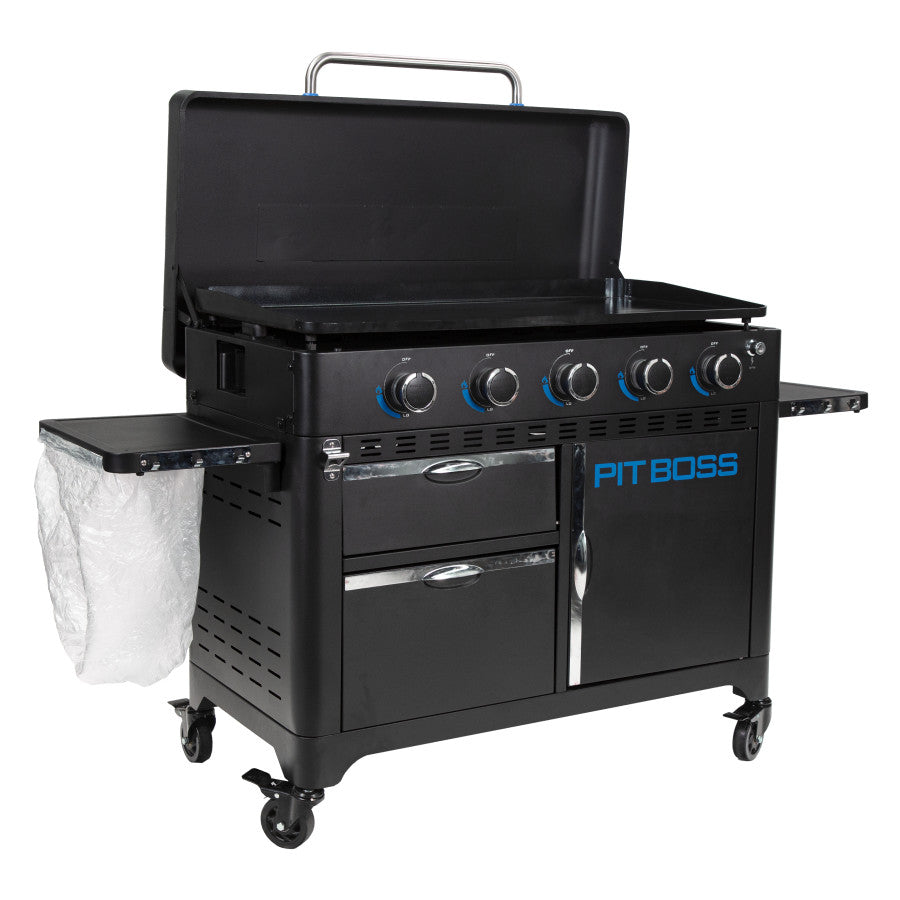 lifestlye_5, Black griddle with bright blue and silver accents with large blue "pit boss" logo. Shown with trash bag holder and trash bag. Side view. Griddle hood open