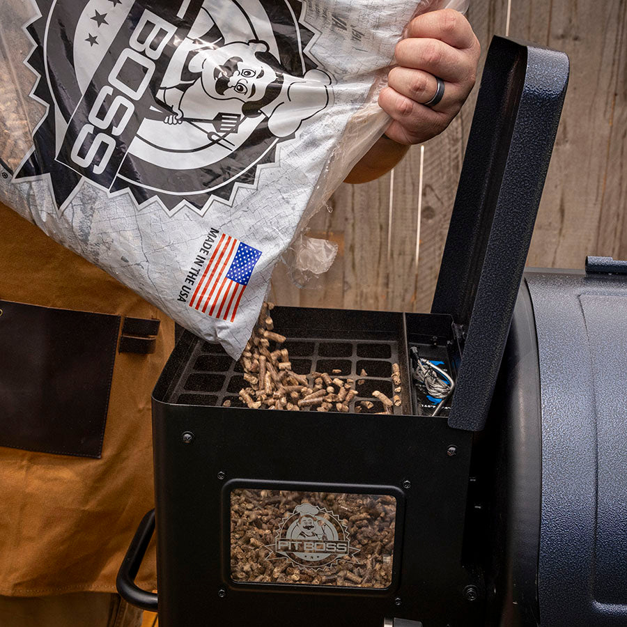 Pit Boss Navigator 850M Wood Pellet Grill 30 lb. Hopper, man pouring hardwood bbq pellets into hopper with viewing window