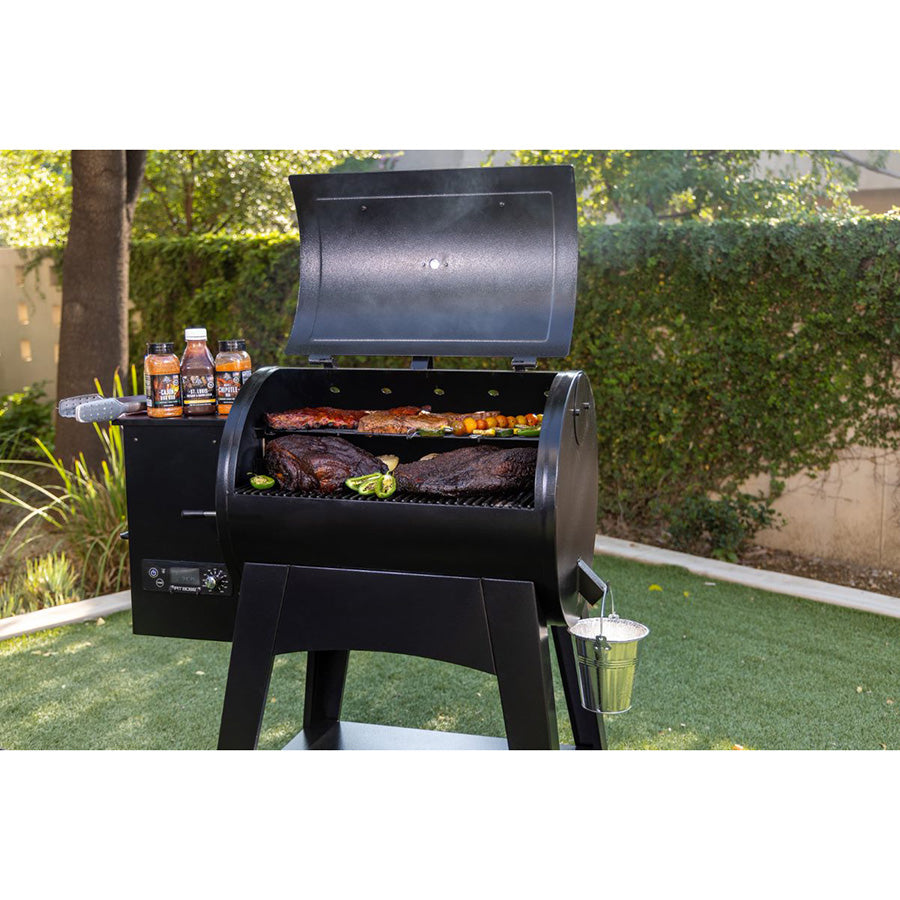 both cooking grates filled with meats and veggies with seasoning on the side of grill