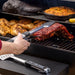 Pit Boss Grills Sportsman 850 Wood Pellet Grill, grilling rack of ribs on smoker with bbq tongs