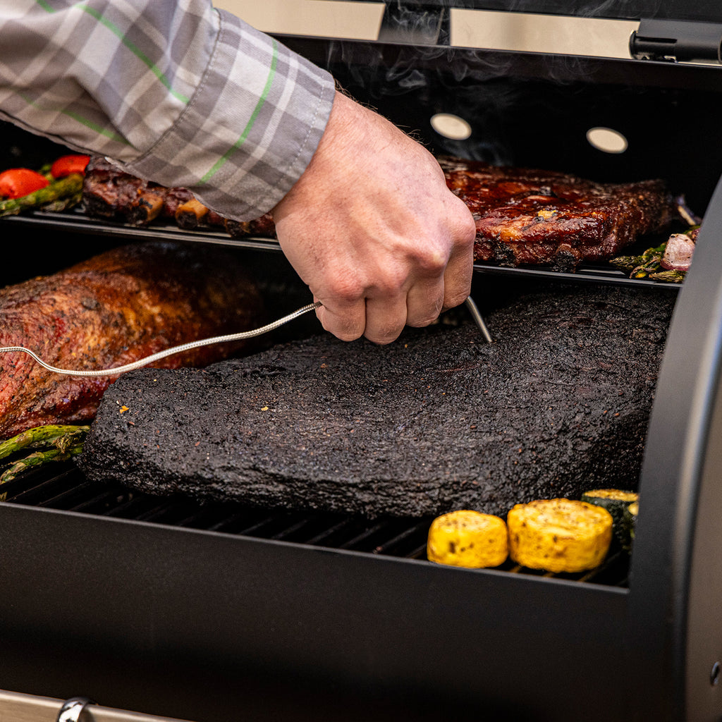Pit Boss Carbon Series 700 wood pellet grill shown from a front angled view with lid open, displaying cooking grates, grilling surface, and meat probes