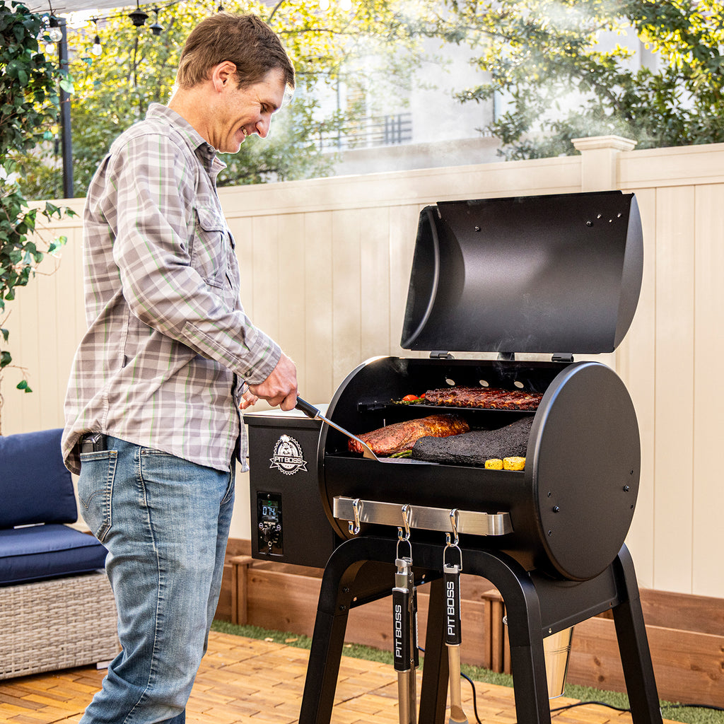 Pit Boss Carbon Series 500 wood pellet grill shown from front angle with lid open, featuring man grilling