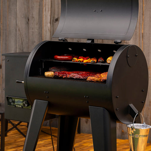 Pit Boss 700FB2 Wood Pellet Grill with meats, ribs, and veggies grilling on cooking racks in backyard