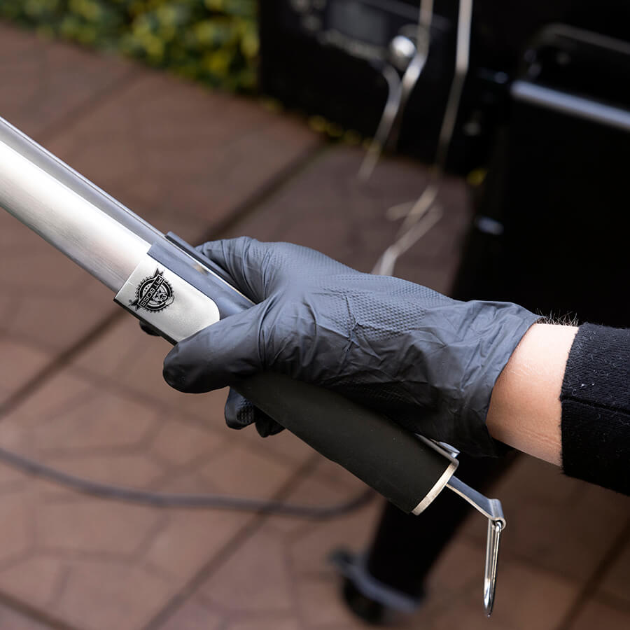 Gray tactical baton with black grip and silver band, held by gloved hand.
