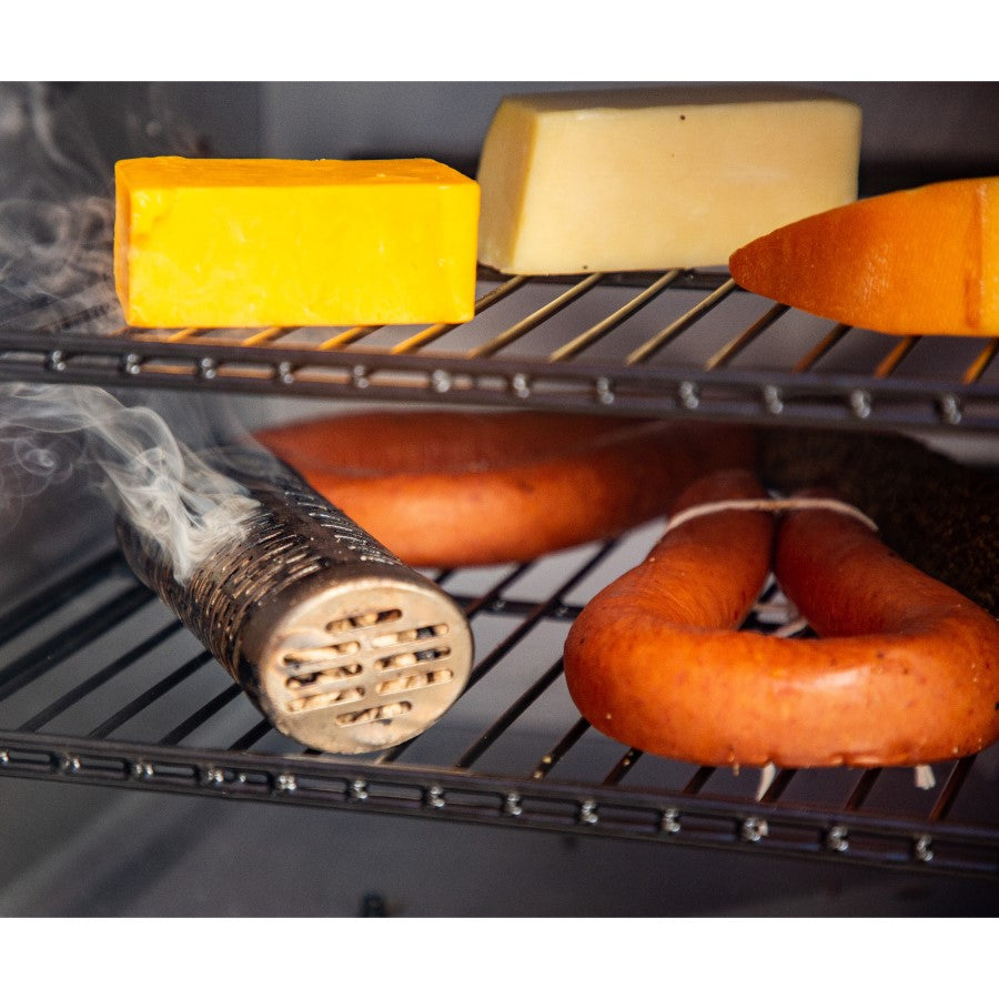 Stainless steel smoker tube releasing smoke in a grill with sausages and cheese on metal racks.