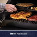 Black electric grill with chicken, ribs, and vegetables cooking, includes one meat probe.