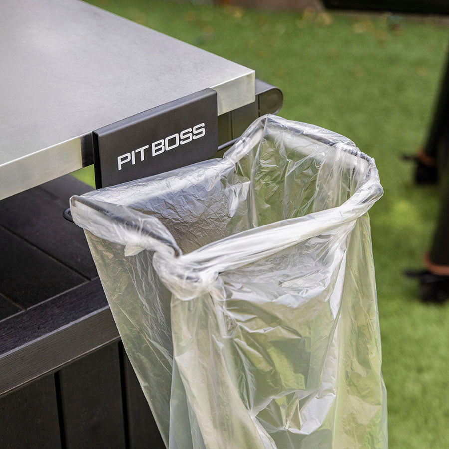 Clear plastic bag attached to a black "PIT BOSS" trash can holder on a grill.