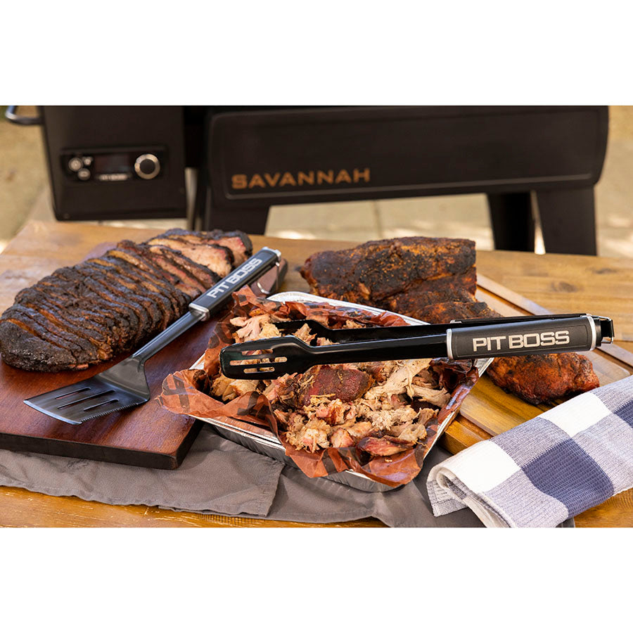 Black Pit Boss BBQ tools with smoked meats on wooden board.