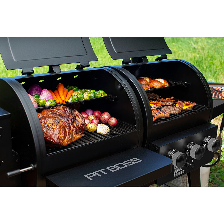 Black Pit Boss grill with open lids, cooking assorted meats and vegetables.