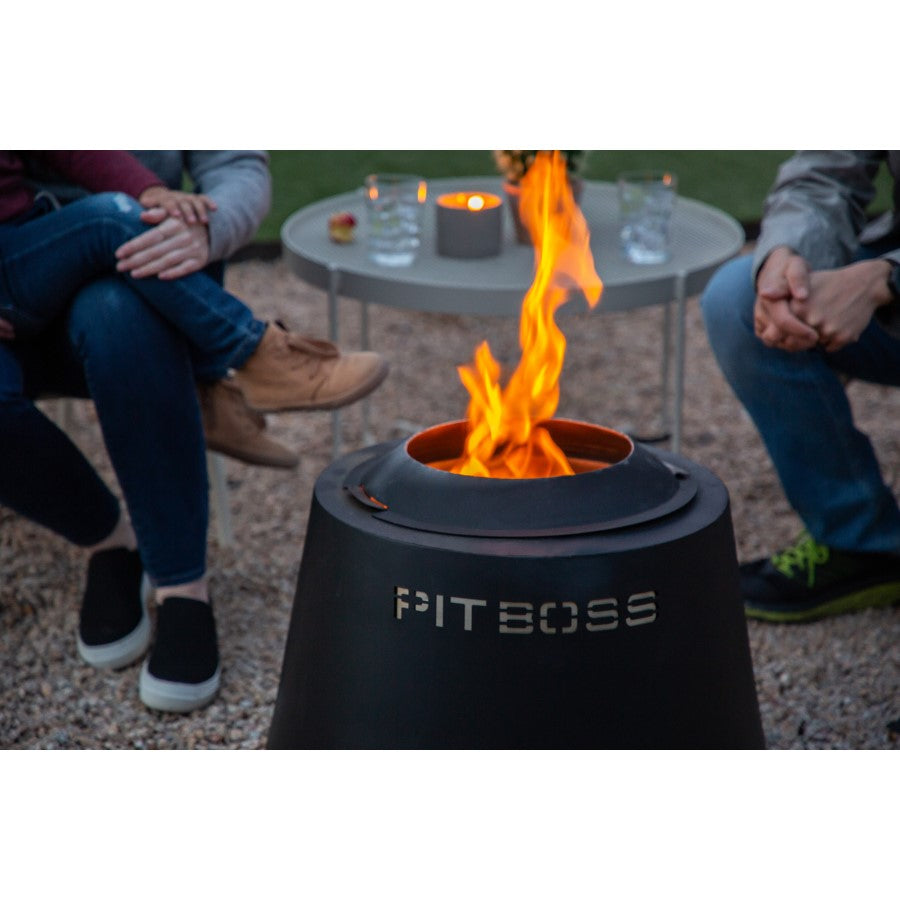 Black Pit Boss portable fire pit with flames, surrounded by people and a table.