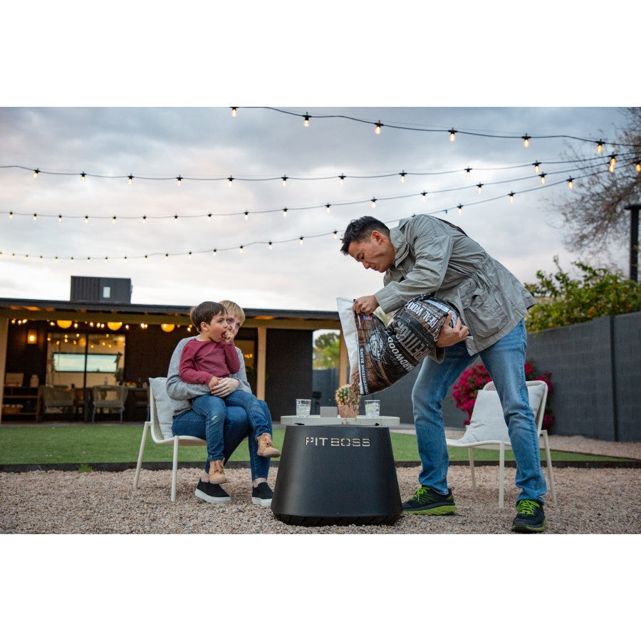 Black Pit Boss portable wood pellet grill with man adding wood pellets.
