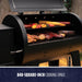 Black grill with 840-square-inch cooking space, featuring meats and vegetables.