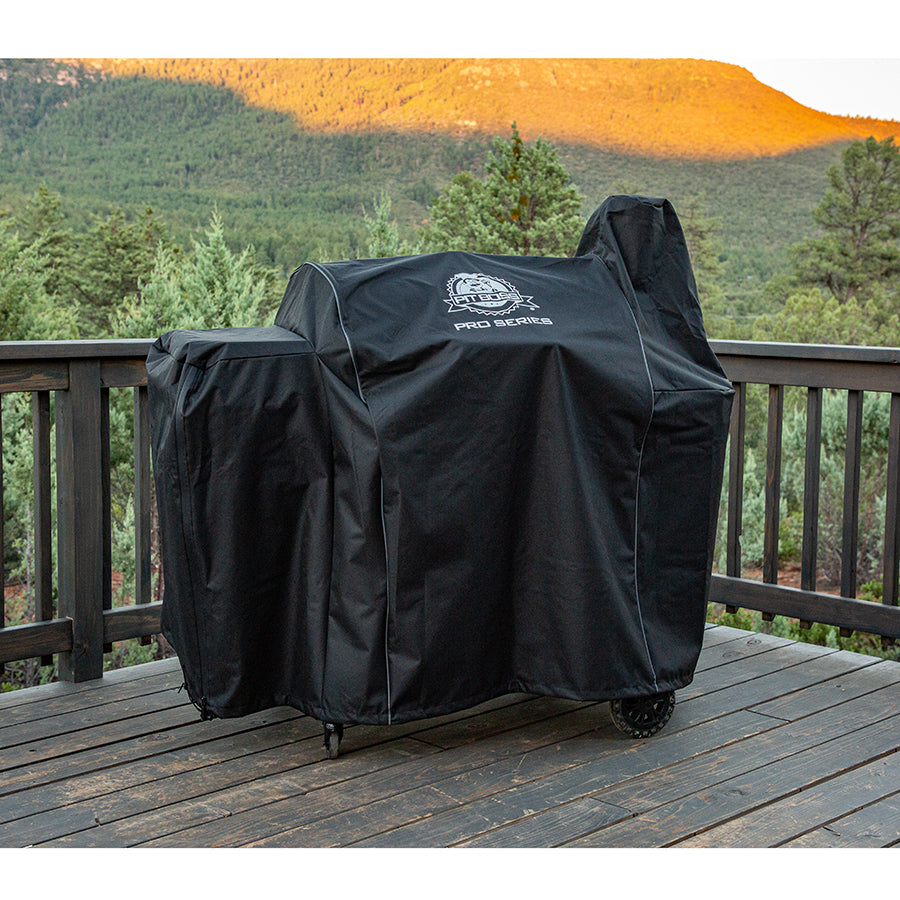 Black grill cover with "Pro Series" logo on wooden deck with mountain view.