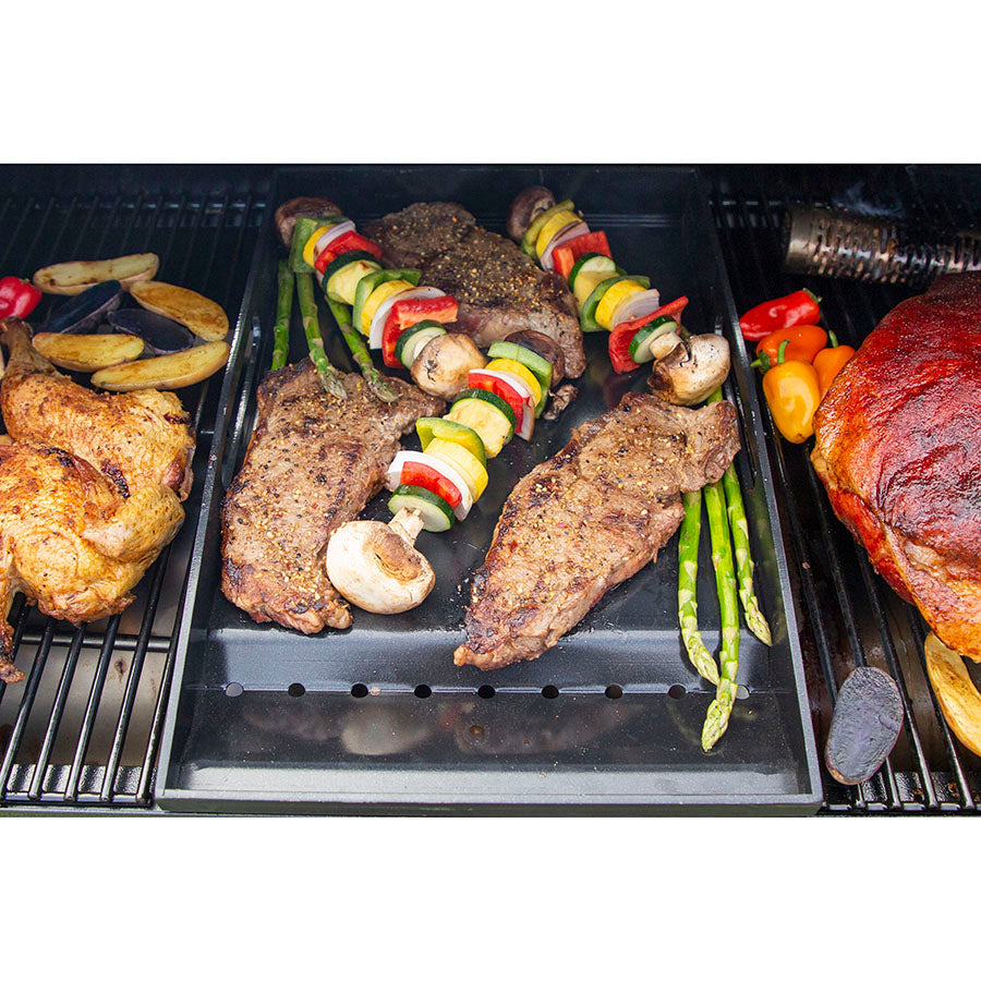 Black grill tray with assorted grilled meats and vegetables.