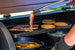 Grill cooking bacon, pancakes, and eggs with tongs.