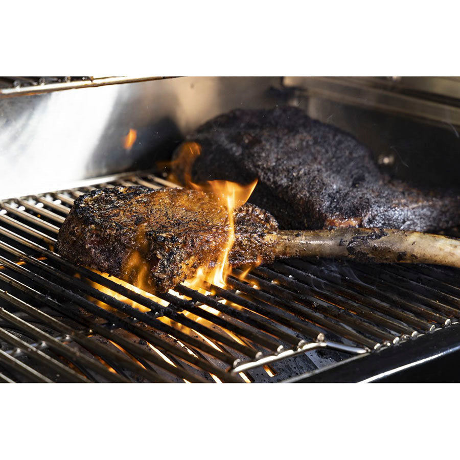 Grilled meat on black grill with flames.