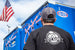 Black Pit Boss t-shirt with logo, worn by person near NHRA trailer.