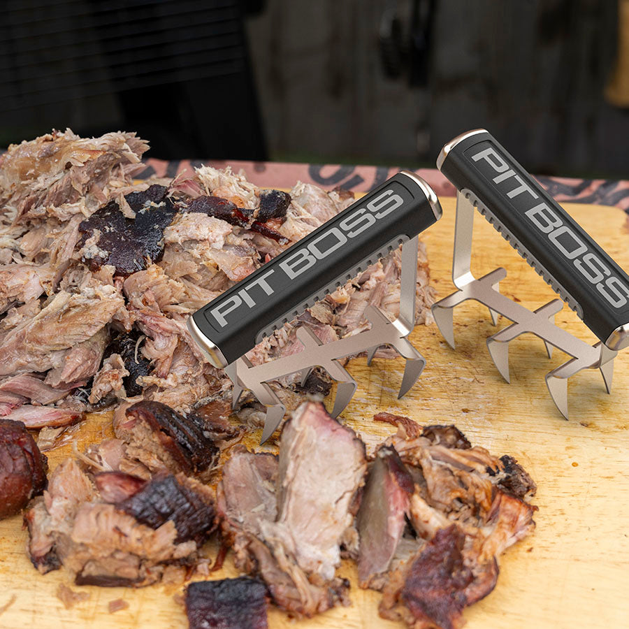 Black Pit Boss meat shredders on wooden cutting board with pulled pork.