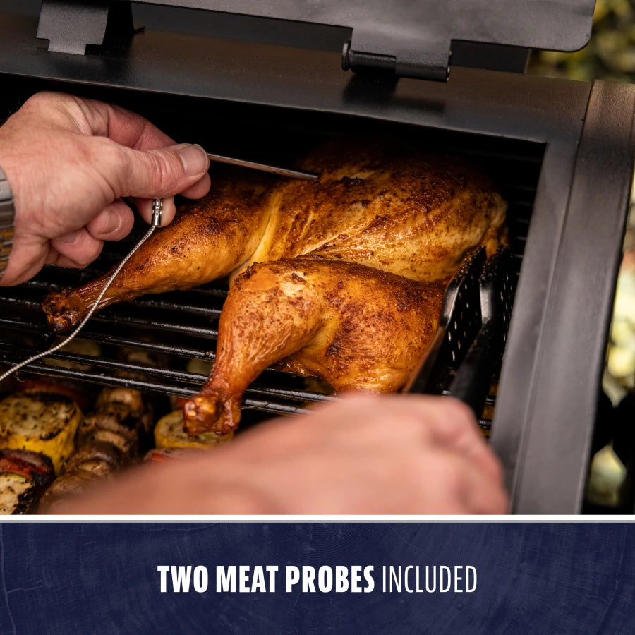 Black grill with two meat probes included, cooking a whole chicken.