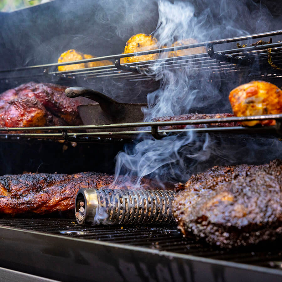 Black grill with smoking wood and corn cooking.