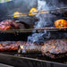 Black grill with smoking wood and corn cooking.