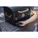 Black PIT BOSS portable power station with hand pulling out power outlet.