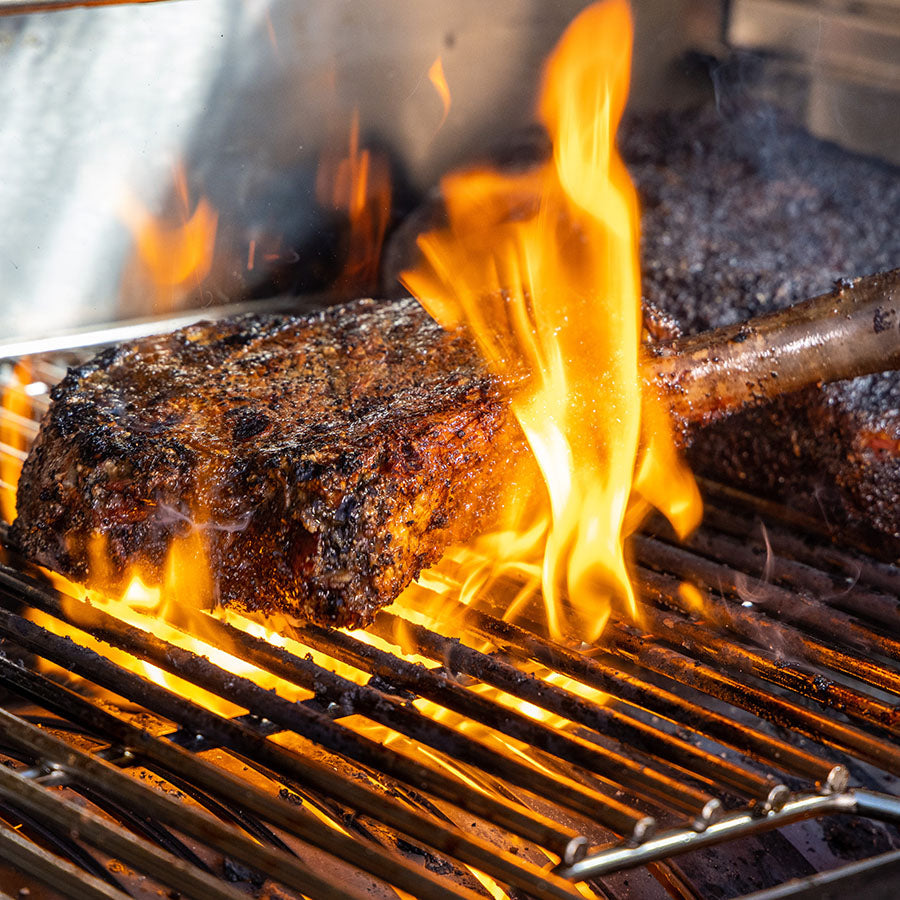 Grilled meat on a flaming barbecue grill.