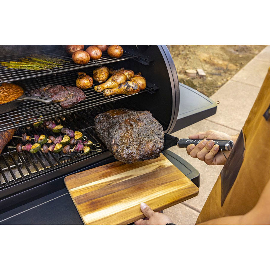 Charcoal grill with multiple racks, cooking assorted meats and vegetables.