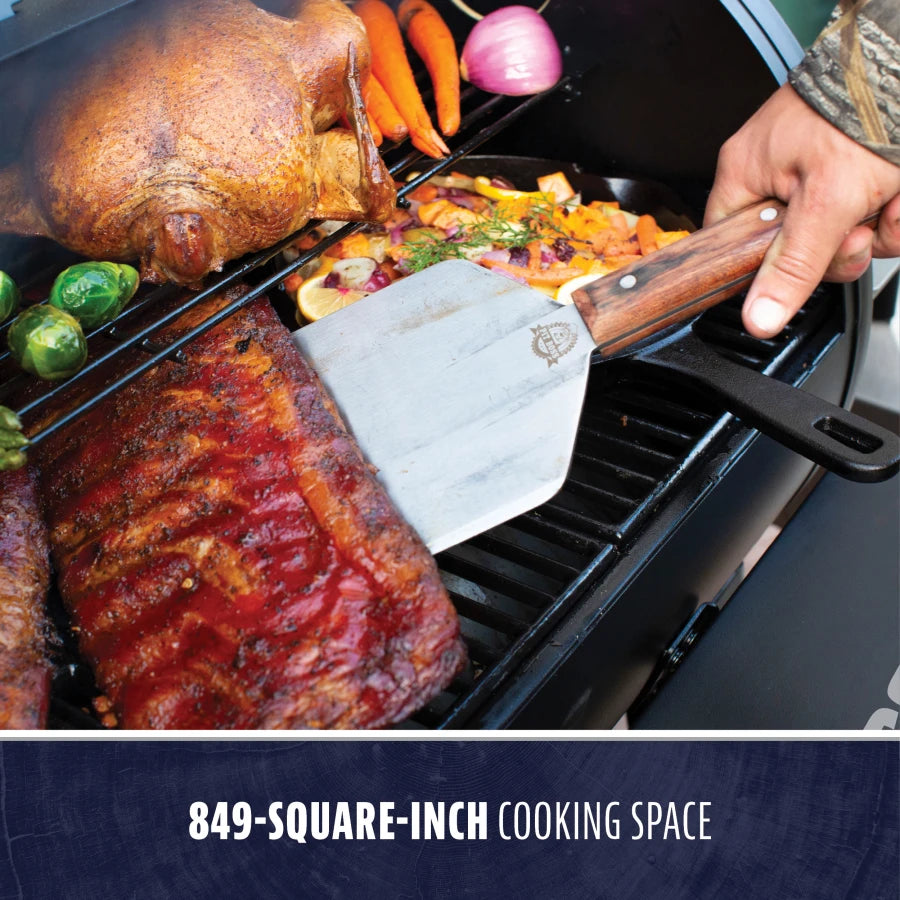 "Large black grill with 849-square-inch cooking space, featuring meats and vegetables."