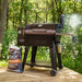 Brown Pit Boss pellet grill with smoker box and wood pellets bag.