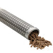 Stainless steel pellet smoker tube with wood pellets spilling out, designed for adding smoke flavor to grilled foods.