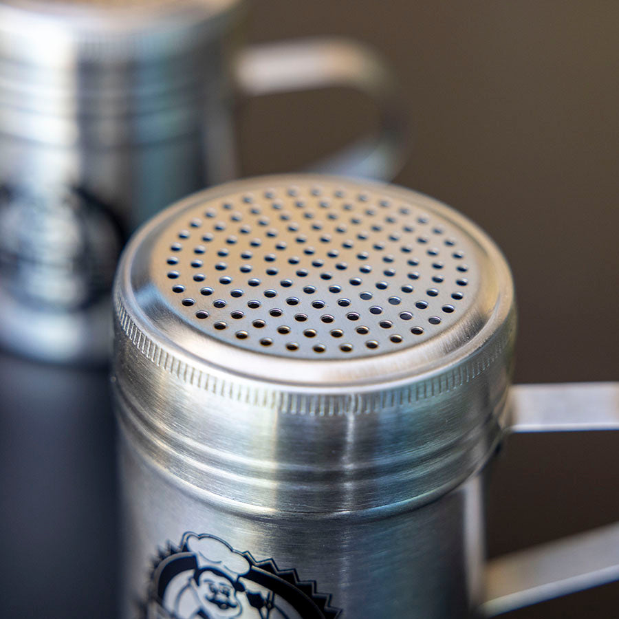 Silver shaker with perforated lid, featuring a chef logo.