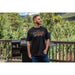 Black Pit Boss t-shirt with "Bigger, Hotter, Heavier" slogan, worn by a man outdoors.