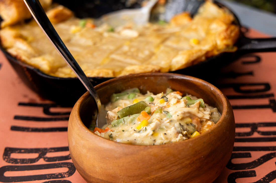 chicken pot pie baked in cast iron and served in wooden bowl