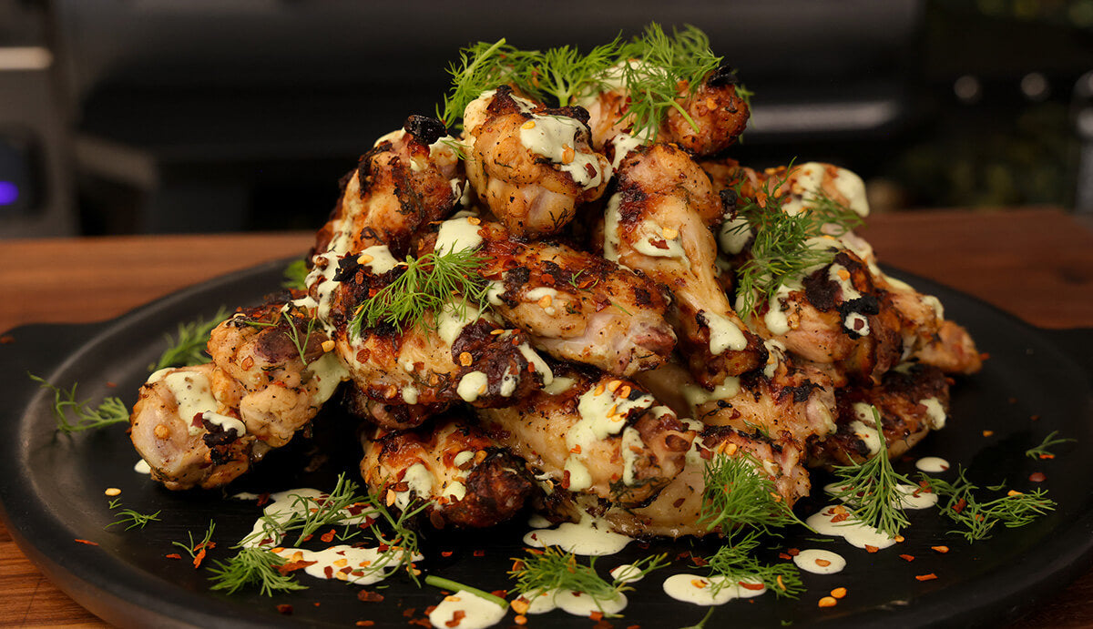 grilled chicken wings with homemade pickle sauce, topped with chili flakes and fresh dill