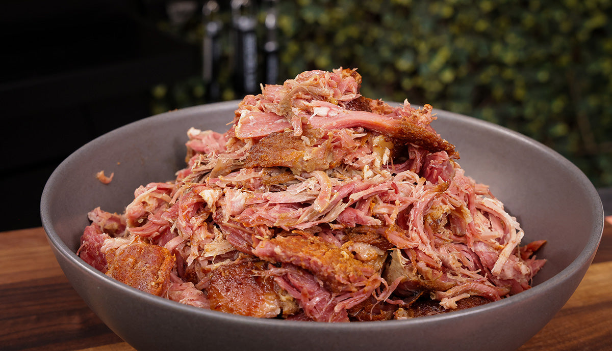 Shredded pastrami pulled pork in grey bowl in backyard 