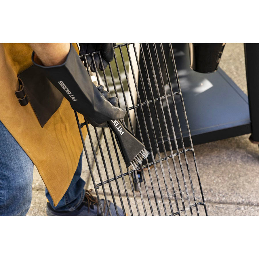 Close up of man carrying grilling rack with Pit Boss gloves and ash broom.