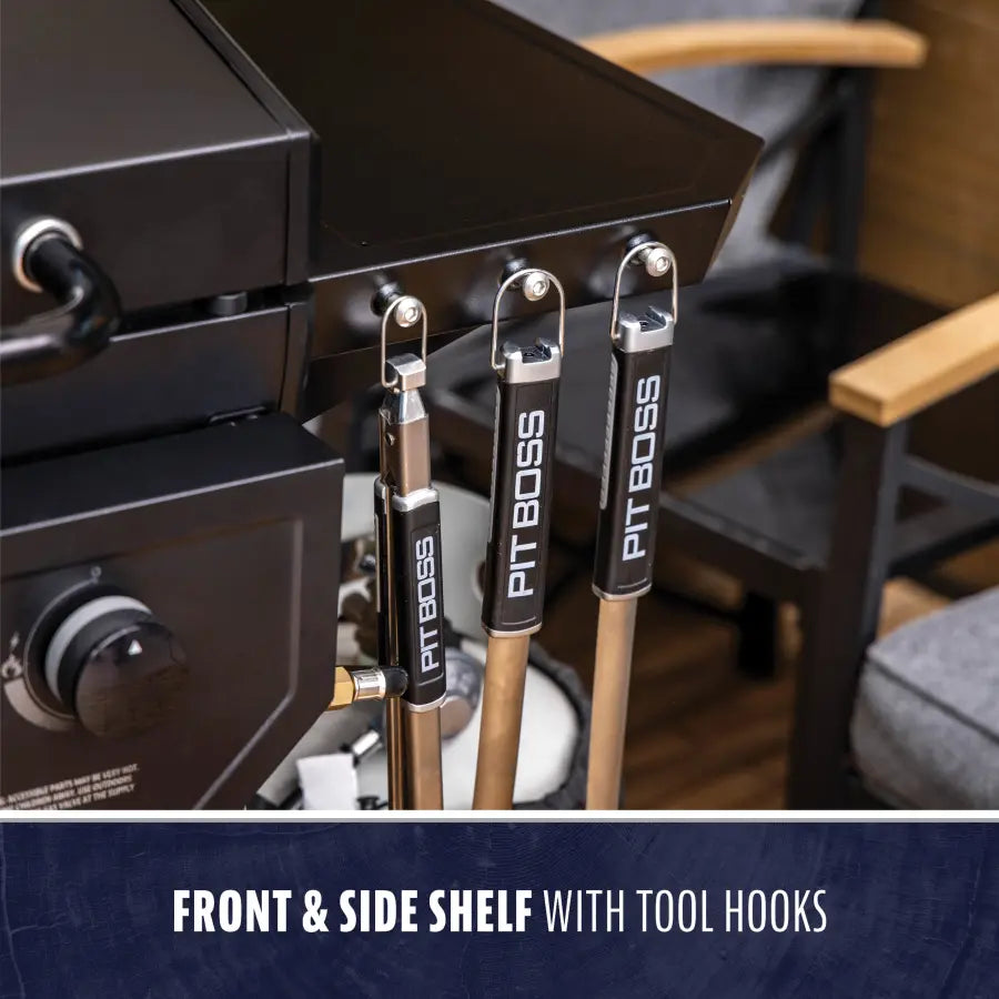 "Black grill with front and side shelf tool hooks labeled 'PIT BOSS'."