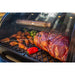 Smoker tube on a grill with smoked meat, chicken wings, Brussels sprouts, and a red pepper. Stainless steel, vented design.