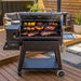 Black Pit Boss Sportsman multi-level grill with various meats and vegetables cooking.