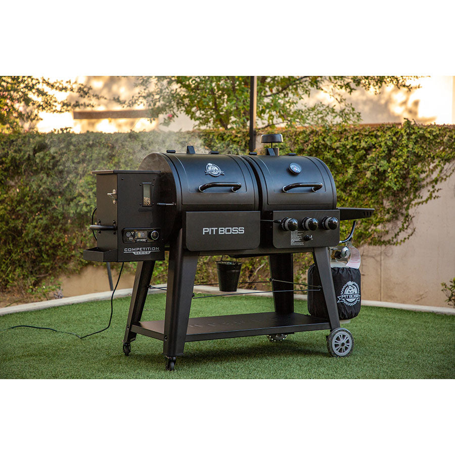 Black Pit Boss Competition Series dual smoker grill with wheels and side shelves.