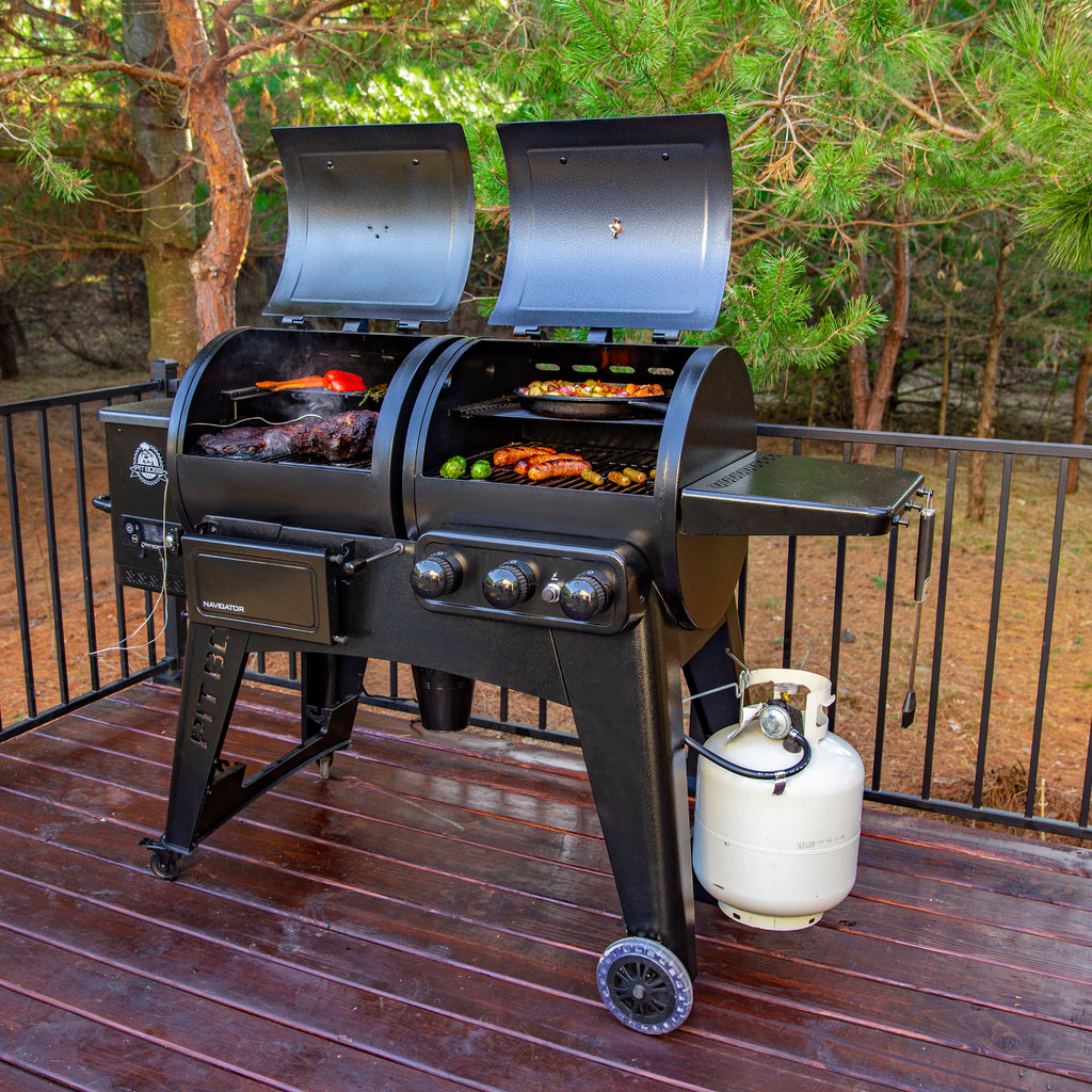 Black dual-burner gas grill with side burner and propane tank, set on wooden deck.