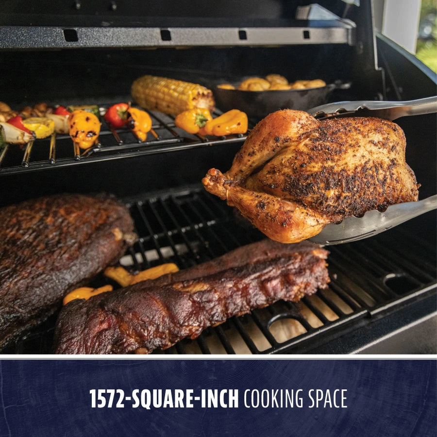 Large black grill with 1572-square-inch cooking space, showcasing grilled meats and vegetables.