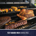 Large black grill with 1572-square-inch cooking space, showcasing grilled meats and vegetables.